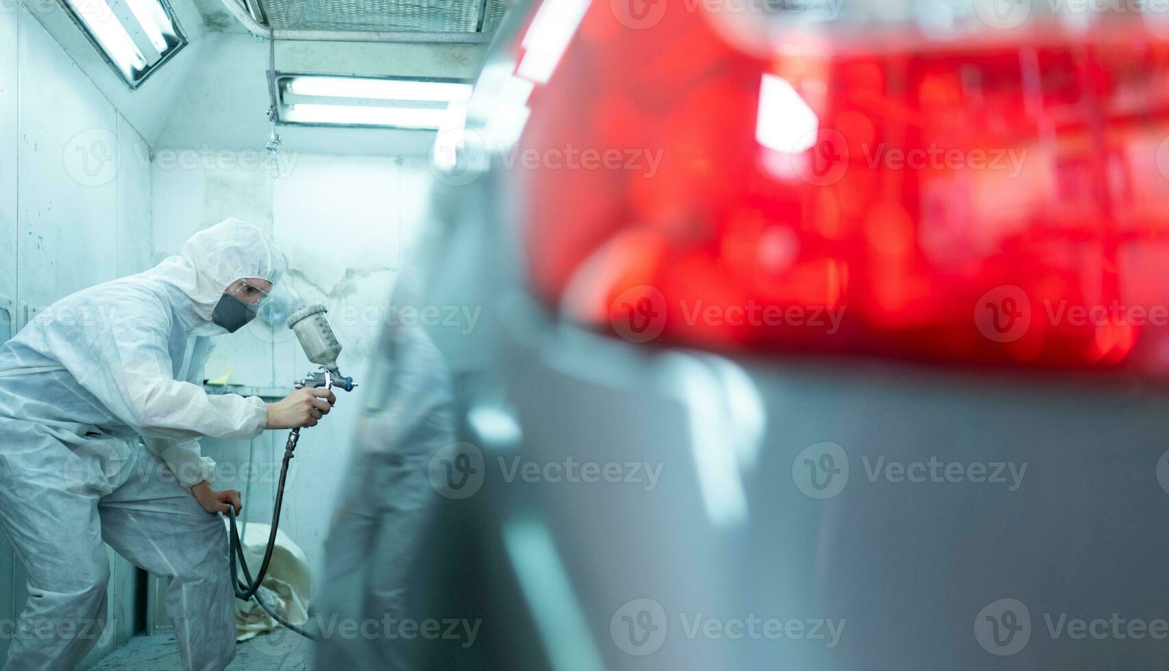 Auto Mechaniker im Auto sprühen Zimmer verwenden ein sprühen Düse injiziert zu das Seite von das Auto Körper mit Pflege zu erstellen Schönheit Das Mischungen mit das Original Farbe von das Wagen. foto