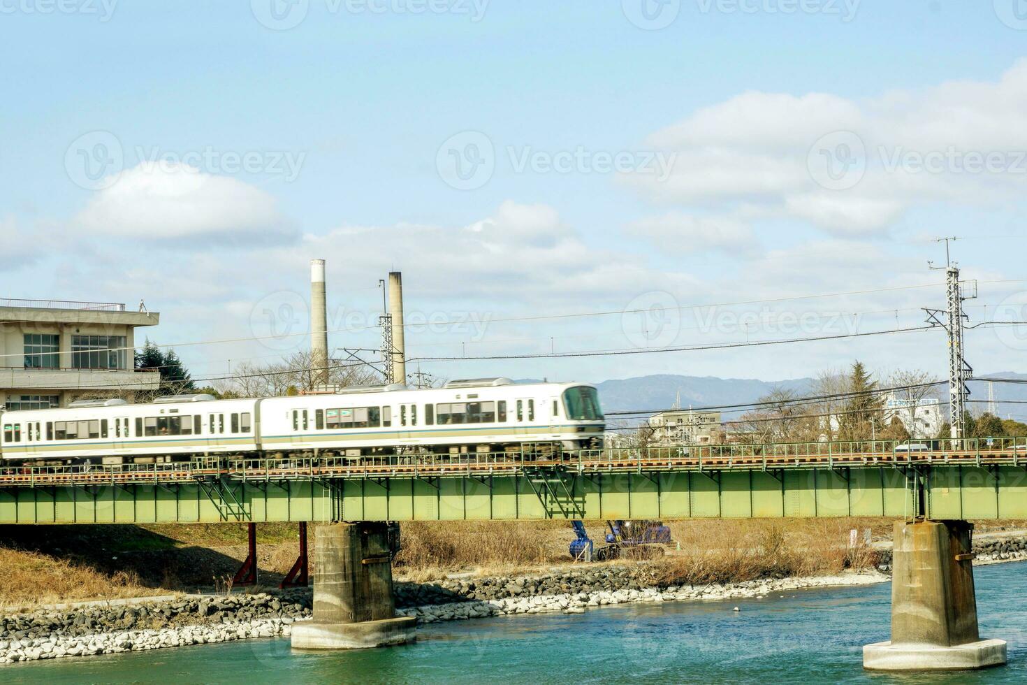 Nahansicht Weiß Zug ist Kreuzung ein Fluss durch das Brücke unter hell Blau Himmel mit Baumwolle Wolke. foto