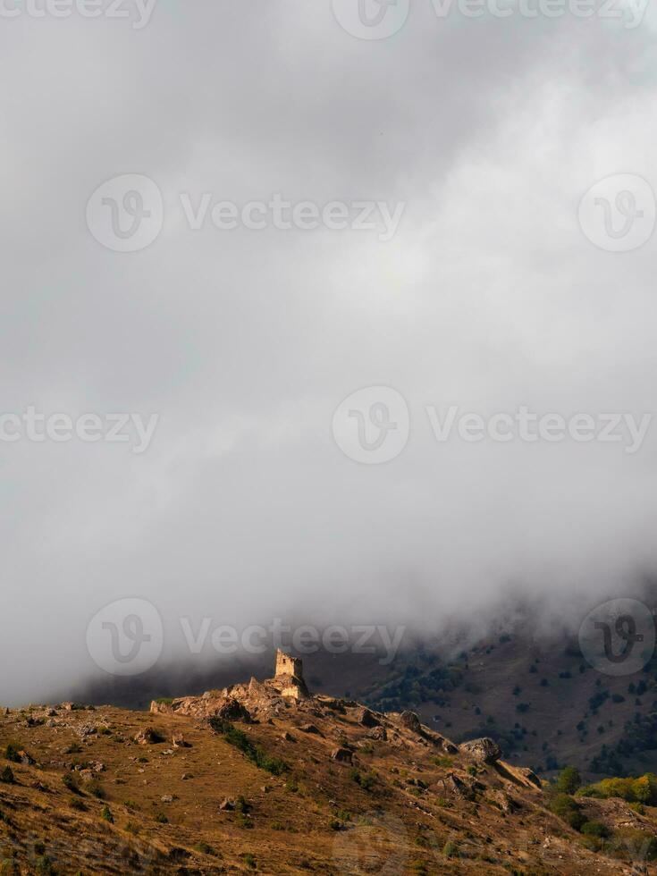 schön dramatisch Landschaft Natur Aussicht im das Berge. alt ossetisch Schlacht Turm im das neblig Berge. Digoria Region. Norden Ossetien, Russland. Vertikale Sicht. foto