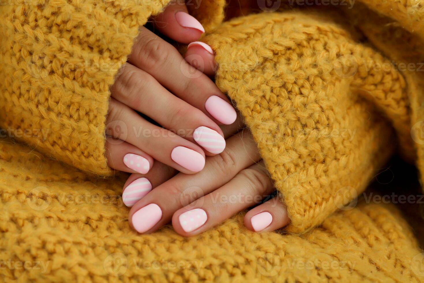 weiblich Hände mit schön oval geformt Nägel, matt Rosa Maniküre Nahansicht auf ein gestrickt Sweatshirt Hintergrund. Schellack. Kopieren Raum foto