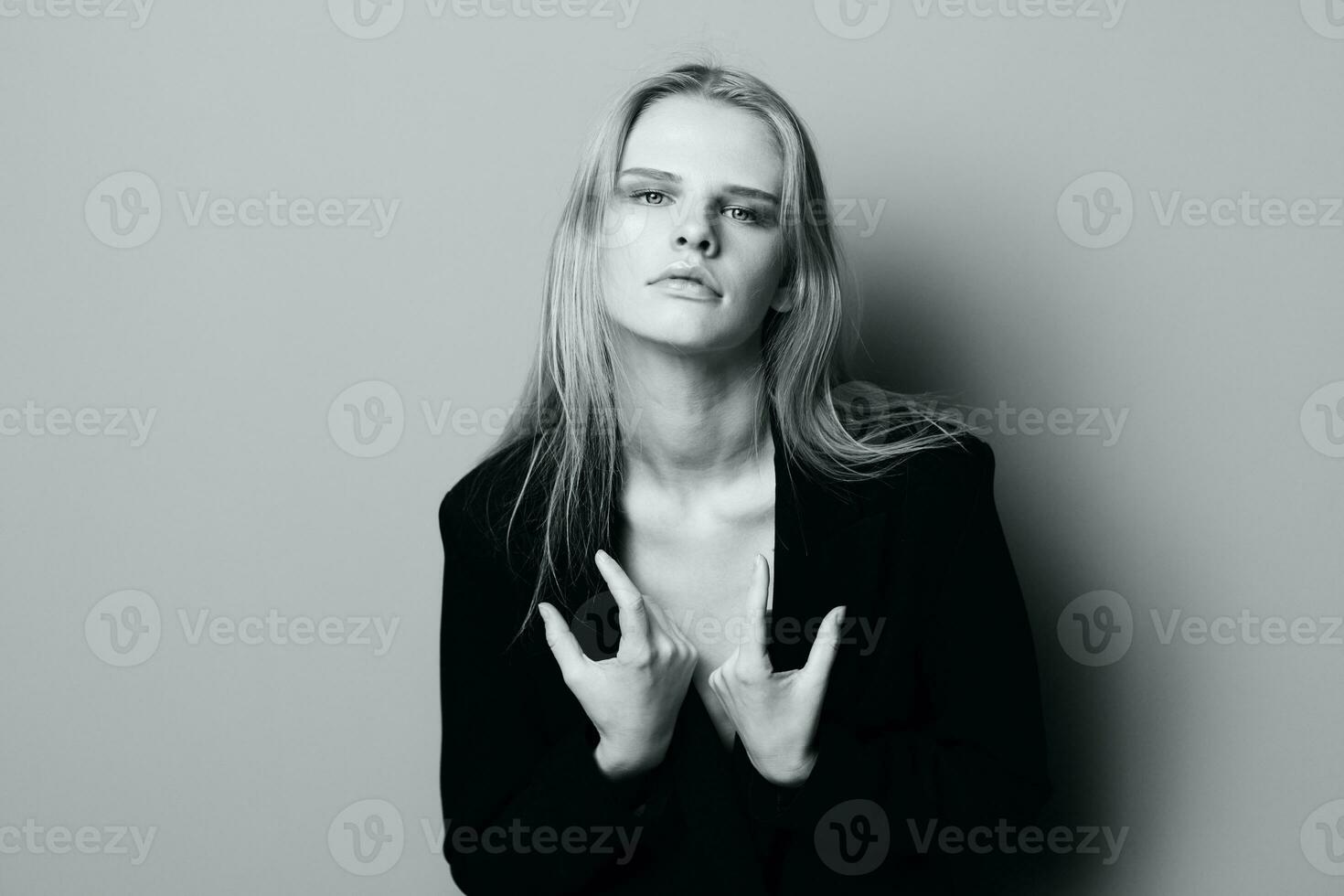 Herrlich jung stilvoll Dame im Jacke posieren gelehnt auf das Mauer beim Studio. ziemlich weiblich blond Modell- sexy suchen beim Kamera foto