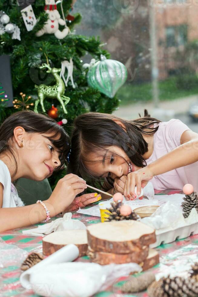 zwei wenig Schwestern haben Spaß während Herstellung Weihnachten Geburt Kunsthandwerk mit beim Zuhause - - echt Familie foto