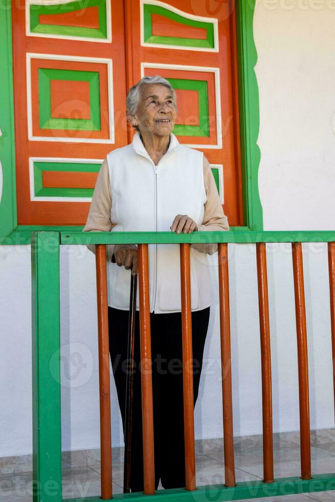 Senior Frau beim ein traditionell bunt Balkon im das schön kolonial Stadt, Dorf von Salento im das Region von quindio im Kolumbien foto