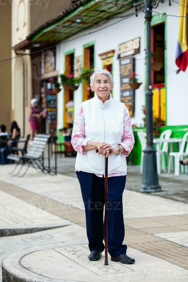 Senior Frau beim ein traditionell bunt Straße im das schön kolonial Stadt, Dorf von Salento im das Region von quindio im Kolumbien foto