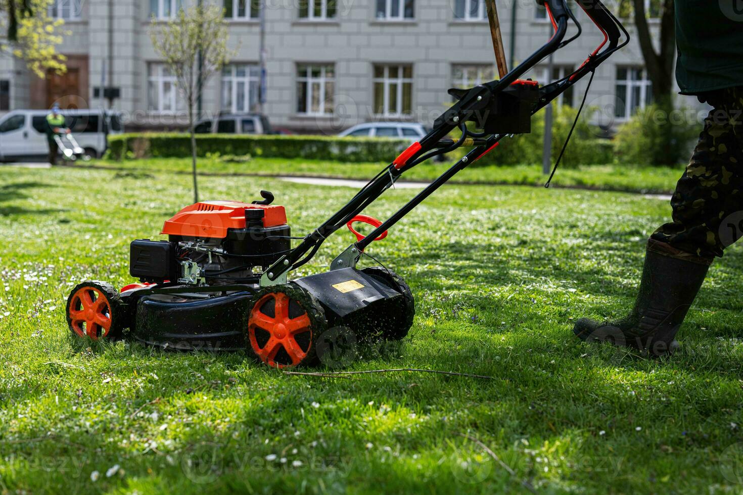 gemeinschaftlich Dienstleistungen Gärtner Arbeiter Mann mit Rasen Mäher zum Gras Schneiden im Stadt Park. foto