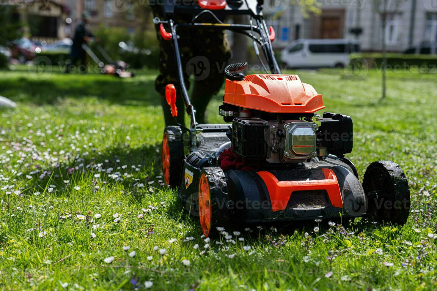 gemeinschaftlich Dienstleistungen Gärtner Arbeiter Mann mit Rasen Mäher zum Gras Schneiden im Stadt Park. foto