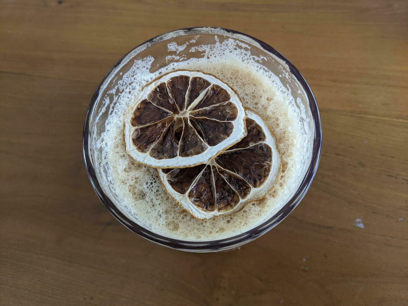 Arabica Kaffee Eis mit getrocknet Zitrone Scheibe mit Sahne schäumen. das Foto ist geeignet zu verwenden zum Kaffee Geschäft Hintergrund, Speisekarte Poster und Kaffee Inhalt Medien.