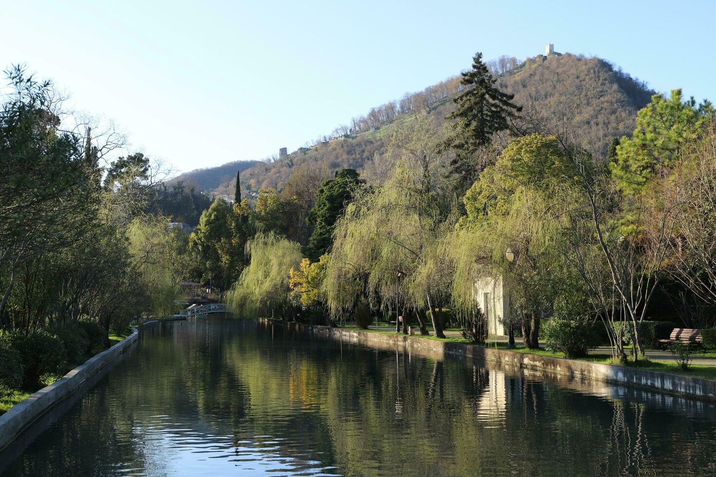 Neu Athos. Abchasien.März, 26, 2023. Strand Park beim Sonnenuntergang im früh frühling.ansicht von das Pondand Bäume auf das Hintergrund von das iverskaja Berg. foto