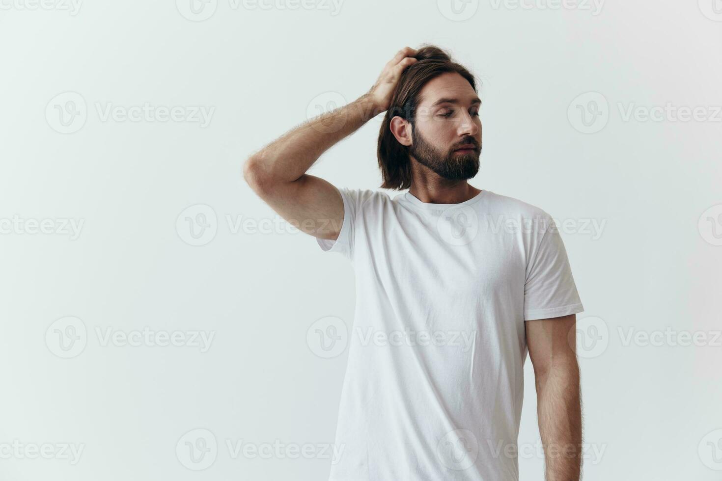 Porträt von ein Mann mit ein schwarz dick Bart und lange Haar im ein Weiß T-Shirt auf ein Weiß isoliert Hintergrund Emotion von Traurigkeit und Sehnsucht foto