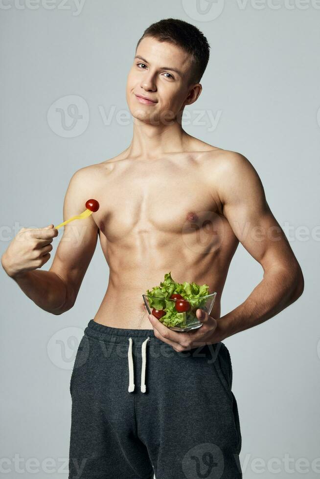 sportlich Mann mit gepumpt oben Abs gesund Essen Salat im Teller trainieren foto