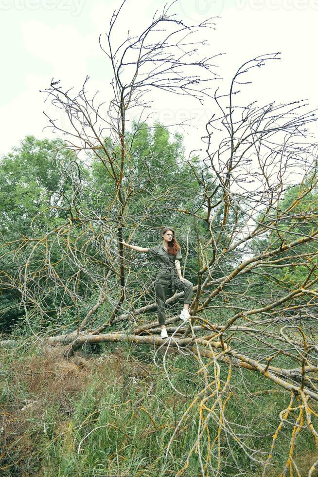 Frau im Overall und gebrochen Baum Turnschuhe Wald foto