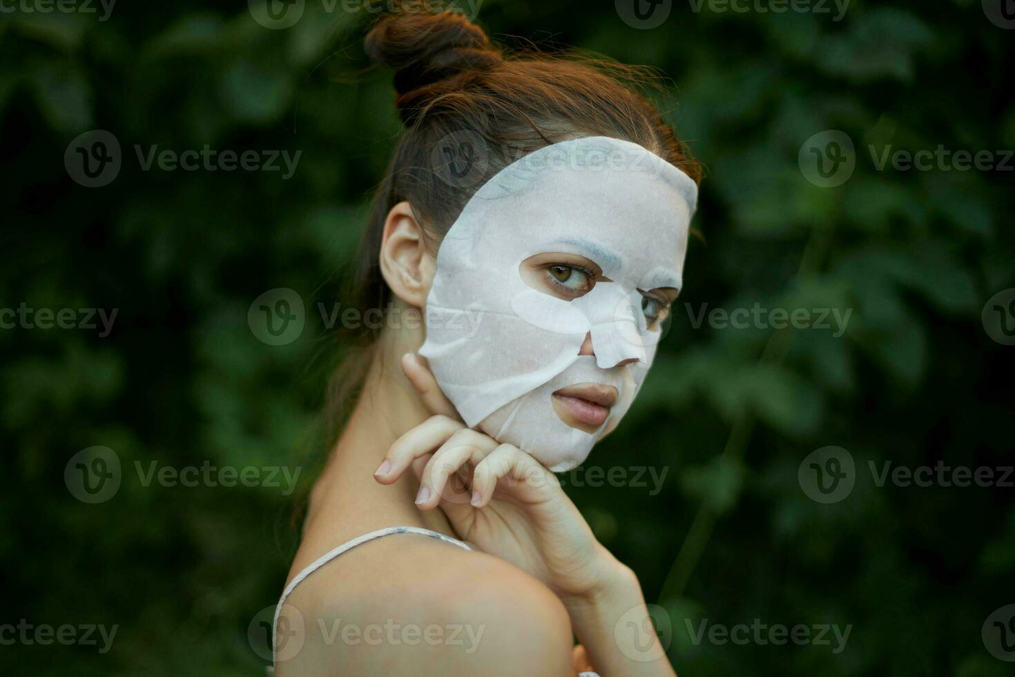 Porträt von ein Frau berührt seine Schulter mit seine Hand Weiß Maske Haut Pflege Gebüsch im das Hintergrund foto