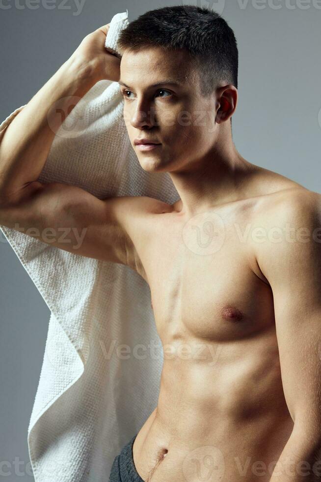 sportlich Kerl mit gepumpt oben Torso Handtücher posieren Fitnessstudio foto