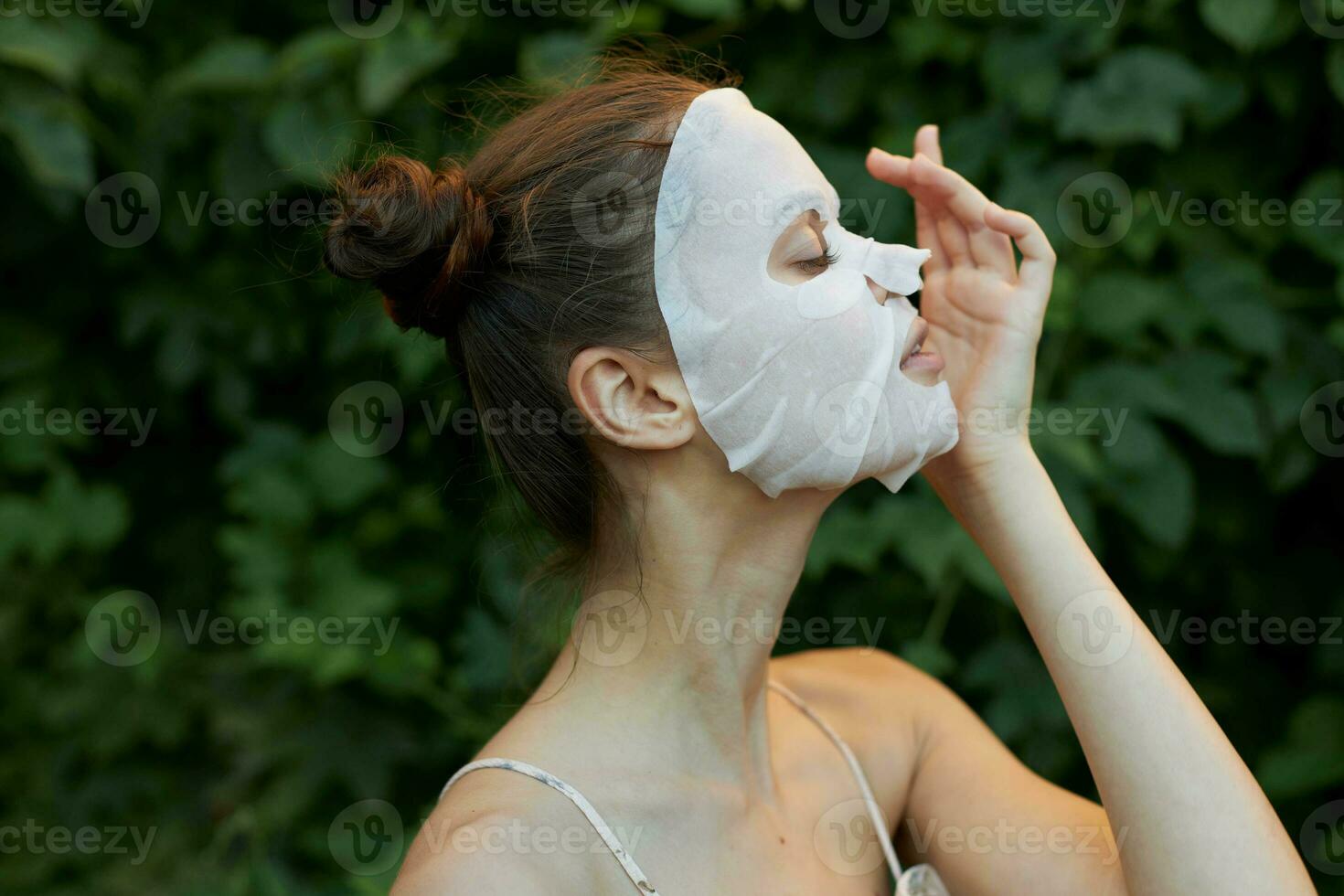 nett Frau Gesicht Maske Kosmetologie Grün Gebüsch im das Hintergrund Nahansicht Seite Sicht. foto