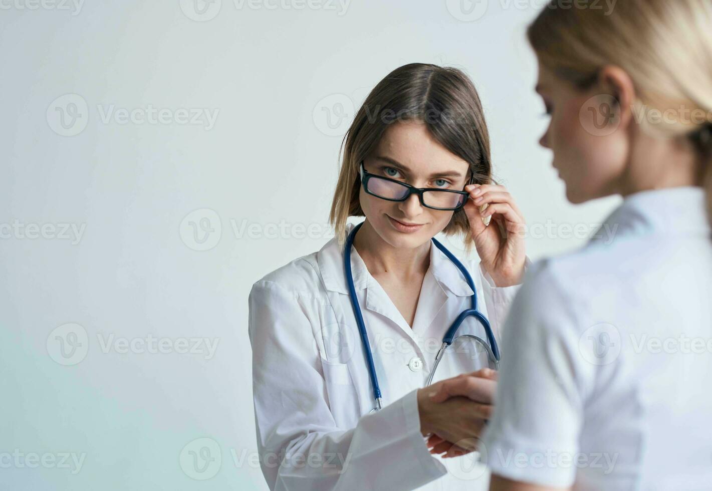 Frau Arzt im ein medizinisch Kleid und Brille mit ein Stethoskop um ihr Hals und ein weiblich geduldig foto