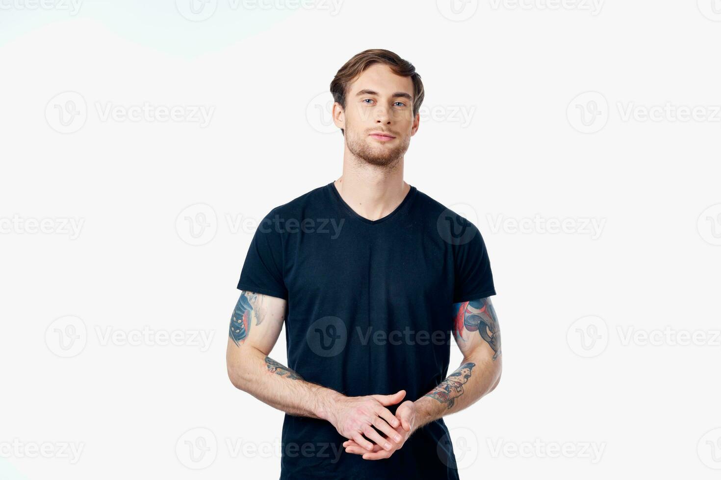 muskulös Mann im ein Blau T-Shirt mit Tätowierungen auf seine Waffen auf ein Licht Hintergrund abgeschnitten Aussicht foto