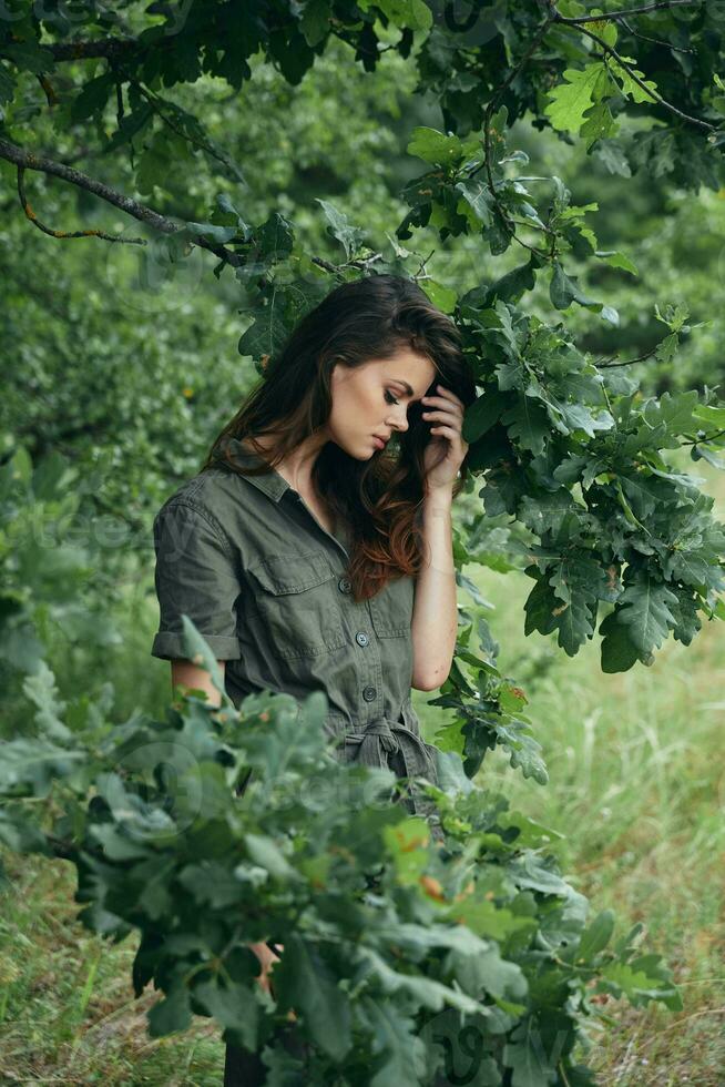 Frau draußen hält ein Baum Ast mit geschlossen Augen foto