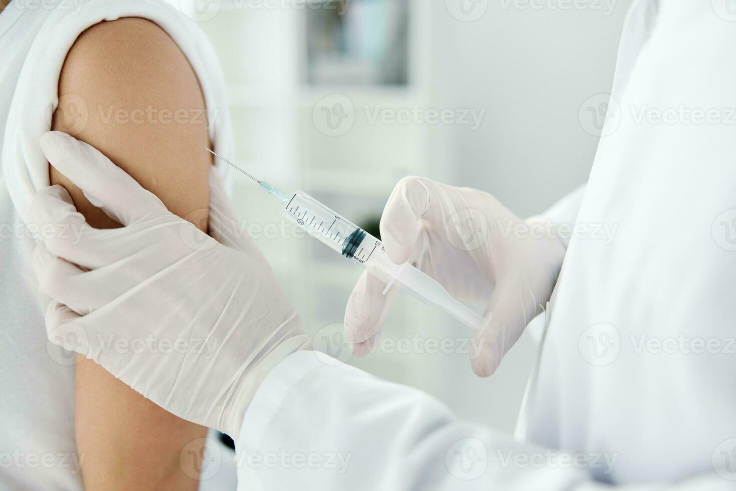 Arzt im schützend Handschuhe hält ein Frau Hand und ein Injektion von covid-19 Impfstoff foto