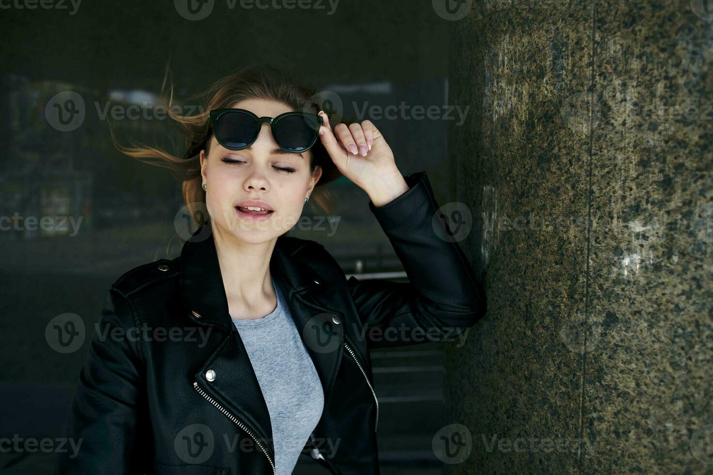 modisch Frau Gehen Nieder das Straße in der Nähe von das Gebäude im Sonnenbrille foto