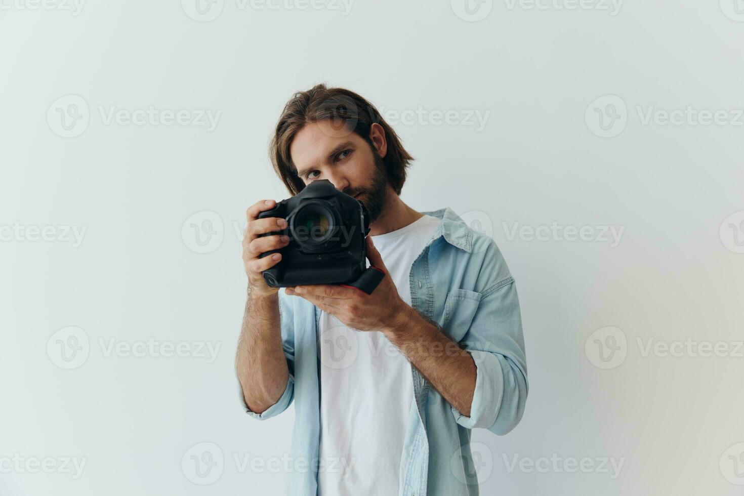 Mann Hipster Fotograf im ein Studio gegen ein Weiß Hintergrund halten ein Fachmann Kamera und Rahmen es oben Vor Schießen. Lebensstil Arbeit wie ein freiberuflich Fotograf foto
