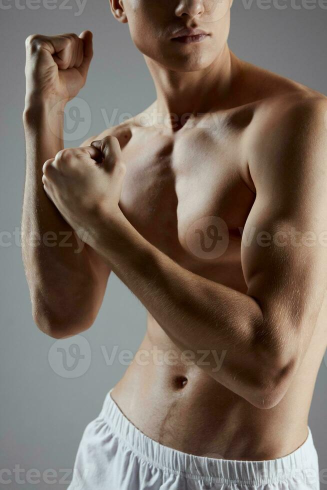 Boxer mit ein aufgepumpt Torso auf ein grau Hintergrund geballt seine Hände in ein Faust Kopieren Raum foto