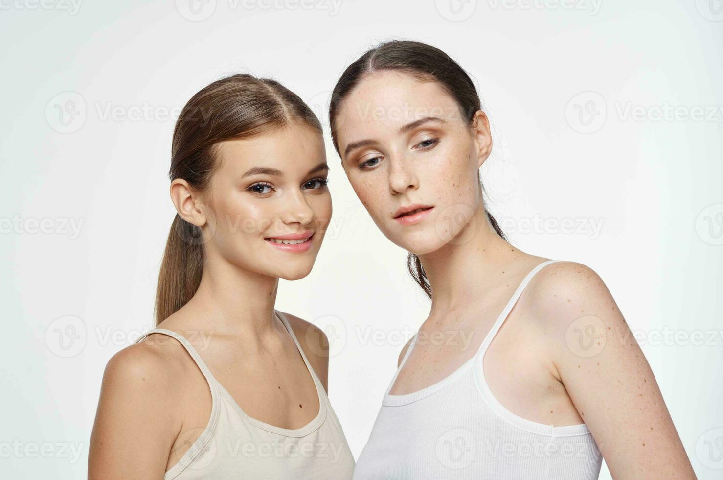 zwei Frauen im Weiß T-Shirts sind umarmen auf ein Licht Hintergrund foto