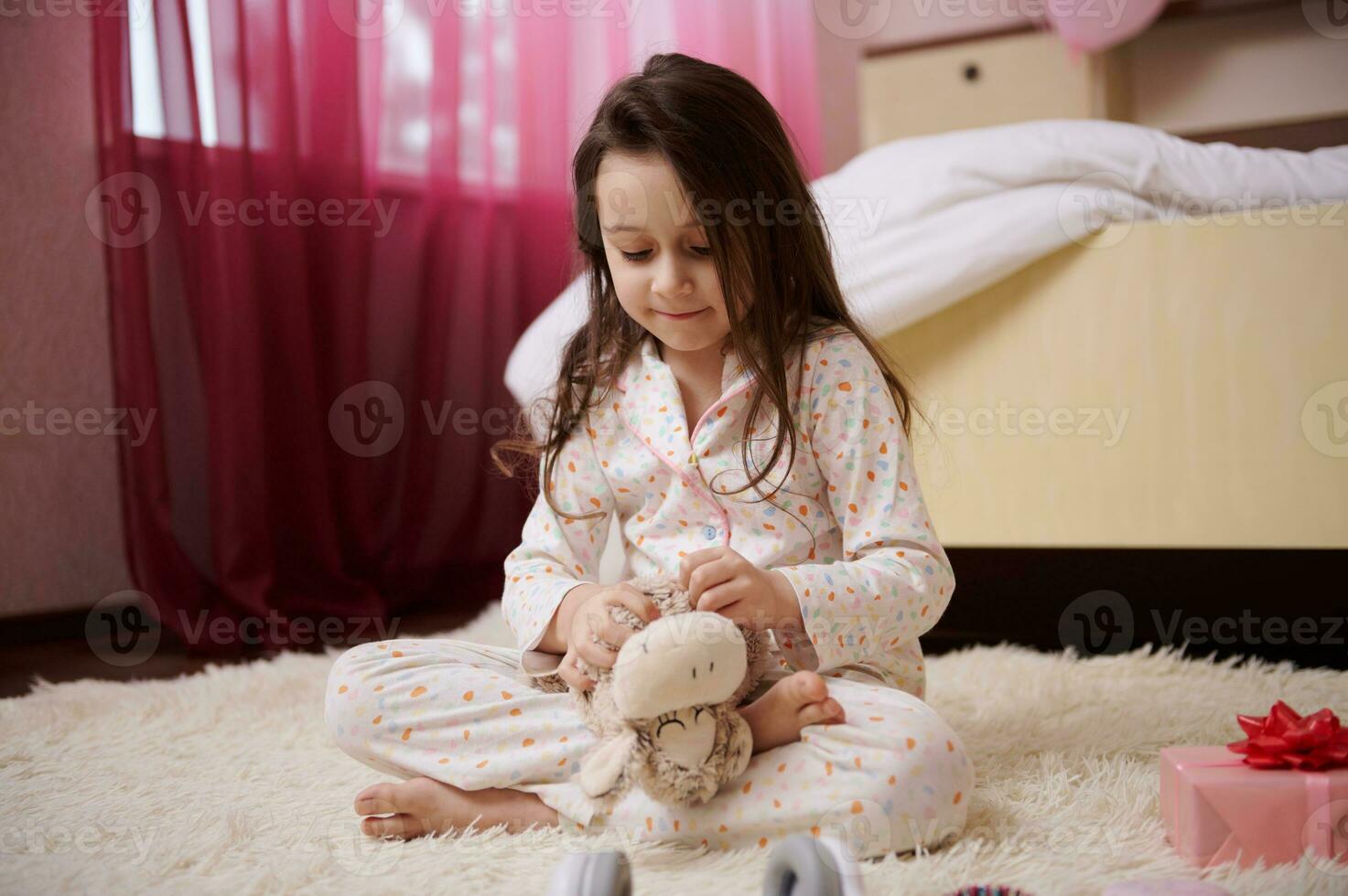 süß wenig Mädchen im stilvoll Pyjama, spielen mit ihr Plüsch Spielzeug Schaf im ihr Zimmer. Kinder und glücklich Kindheit Konzept foto