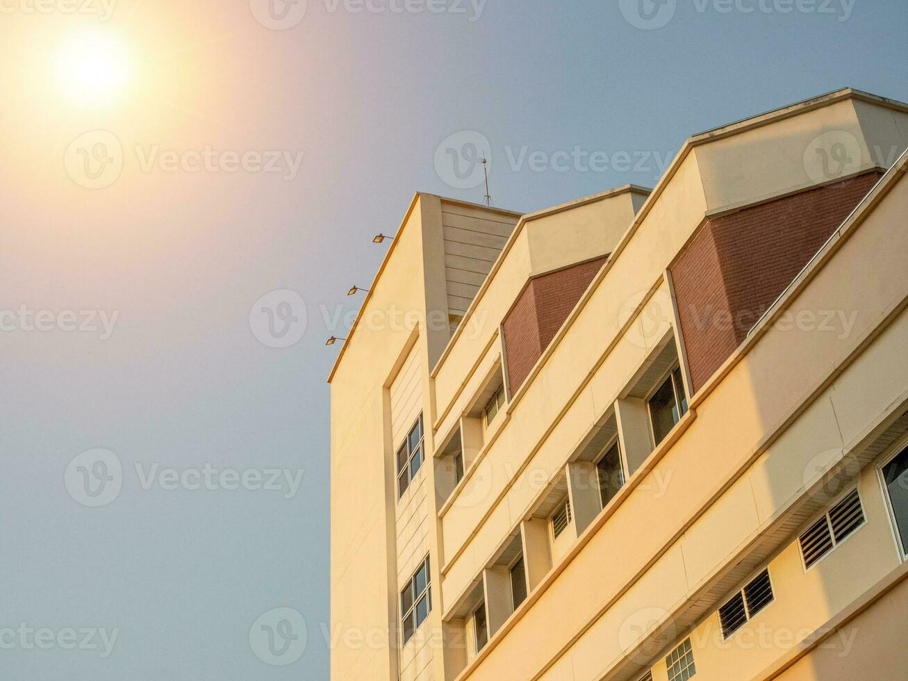 Seite Aussicht von Gelb Beton Gebäude sich schneiden das Orange Sonne. foto