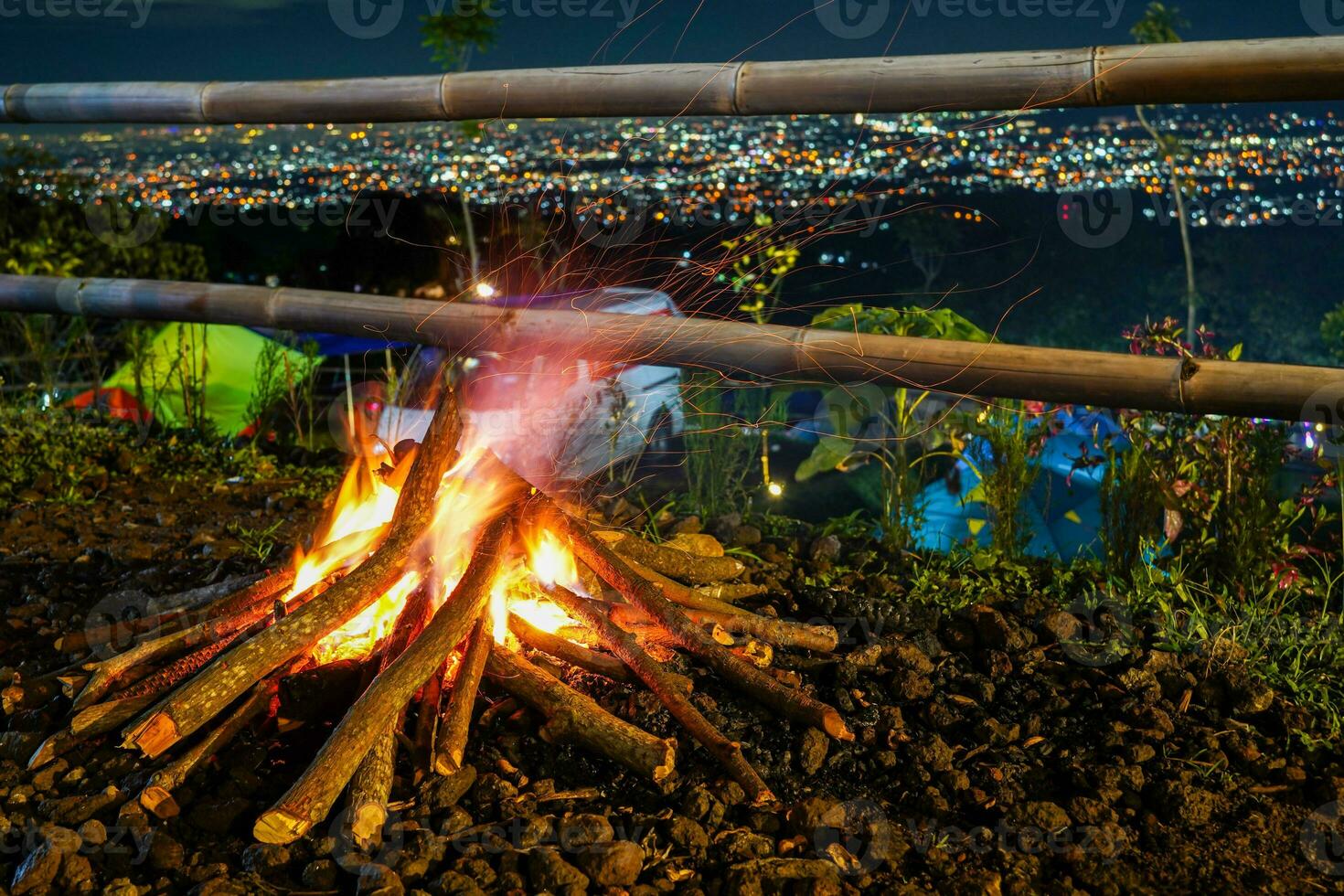 Lagerfeuer und etwas Funken auf das Camping Boden, mit Stadtlicht im das Hintergrund foto