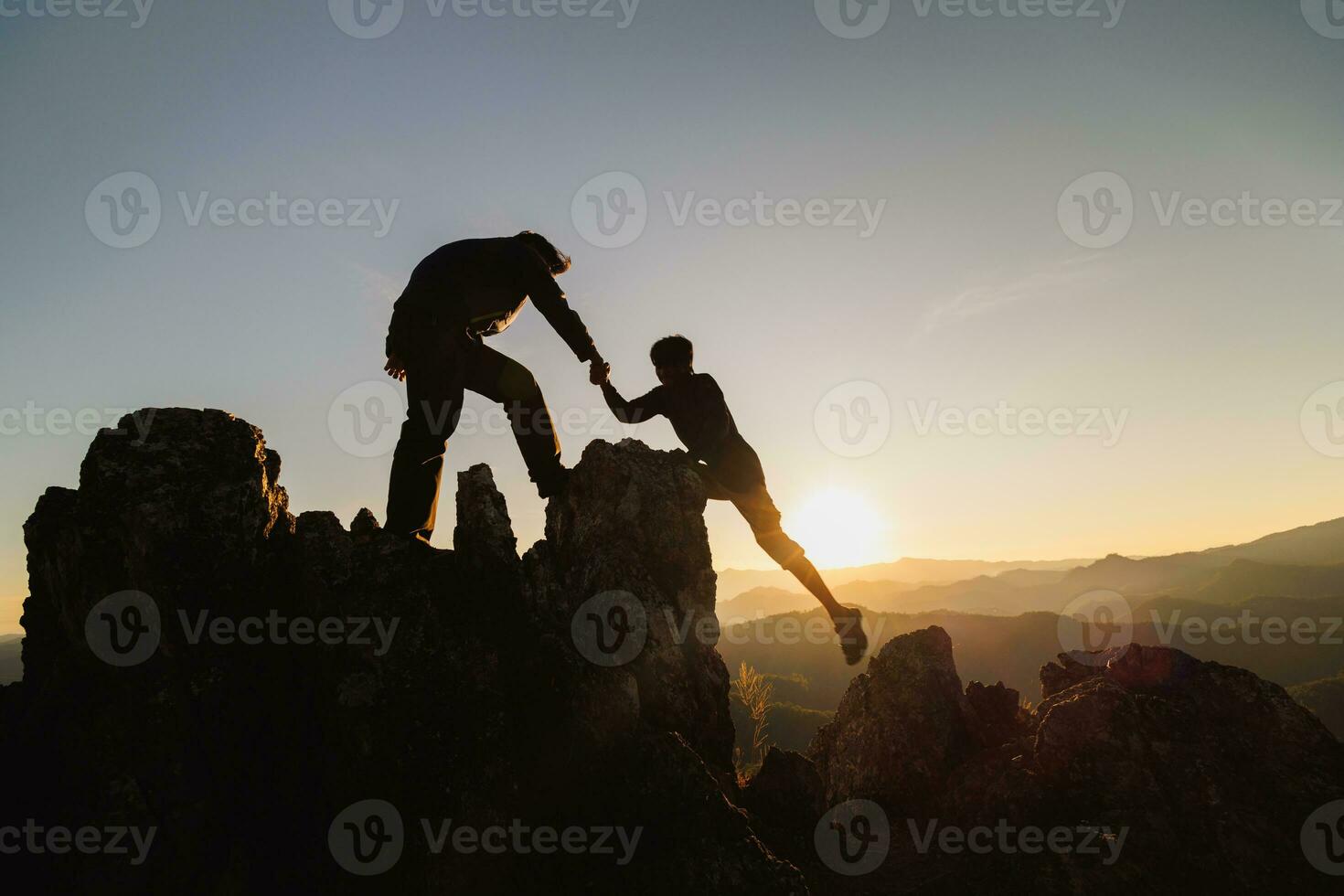 Silhouette der Teamarbeit von zwei Wanderern, die sich auf dem Gipfel des Bergsteigerteams gegenseitig helfen. teamarbeit freundschaft wandern einander helfen vertrauen hilfe silhouette in den bergen, sonnenaufgang. foto