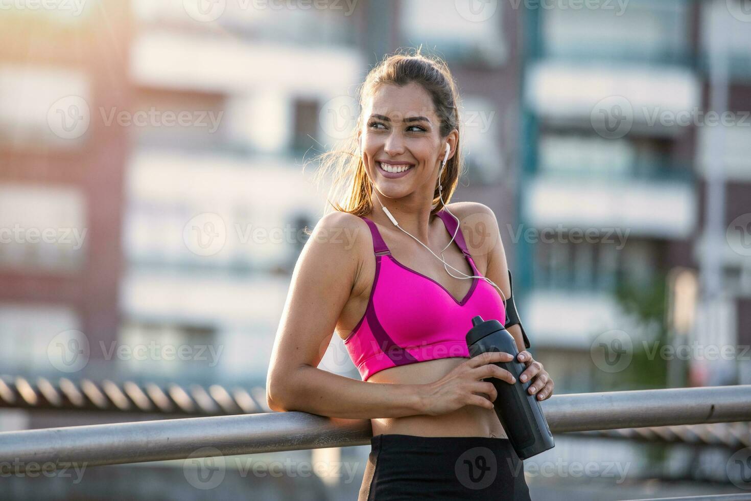 Fitness Frau entspannend nach Übung mit ein Molke Protein Flasche. entspannend nach Ausbildung. schön jung Frau suchen Weg während ruhen nach Laufen foto