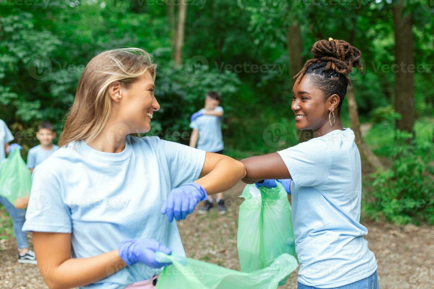 Freiwillige Gruppe Reinigung Park von Müll. jung Frau und Männer Gehen durch Wald und Tragen Plastik Taschen. draussen Reinigung Konzept foto