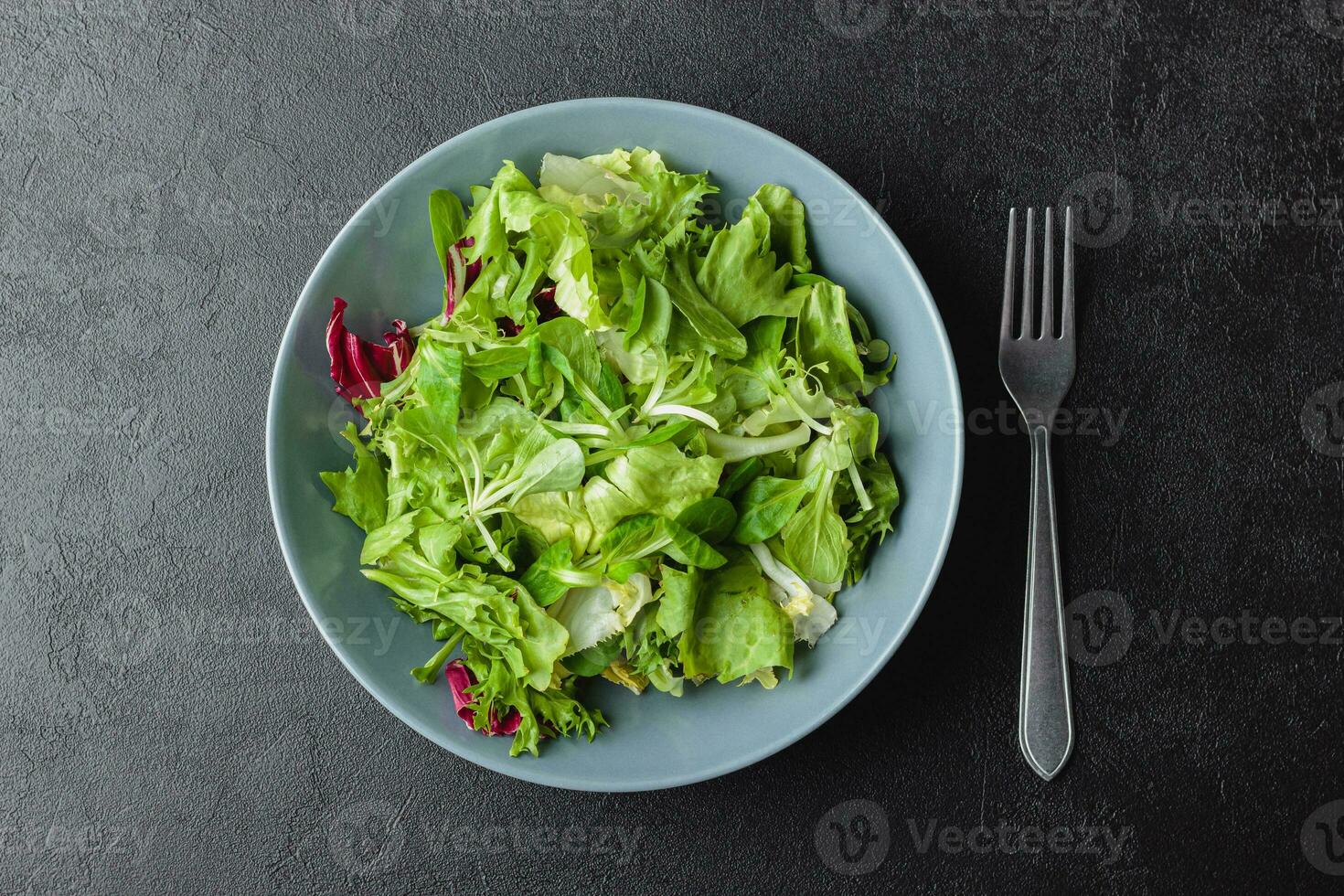 grüne salatblätter in schüssel auf schwarzem tisch. foto