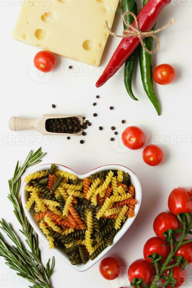 roh Pasta Torti im Herz Schüssel mit Kirsche Tomaten, Käse, Rosmarin, Chili und Piment. foto