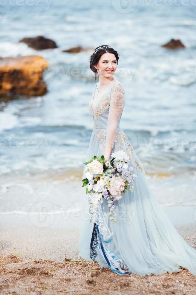 Braut mit einem Blumenstrauß am Strand foto