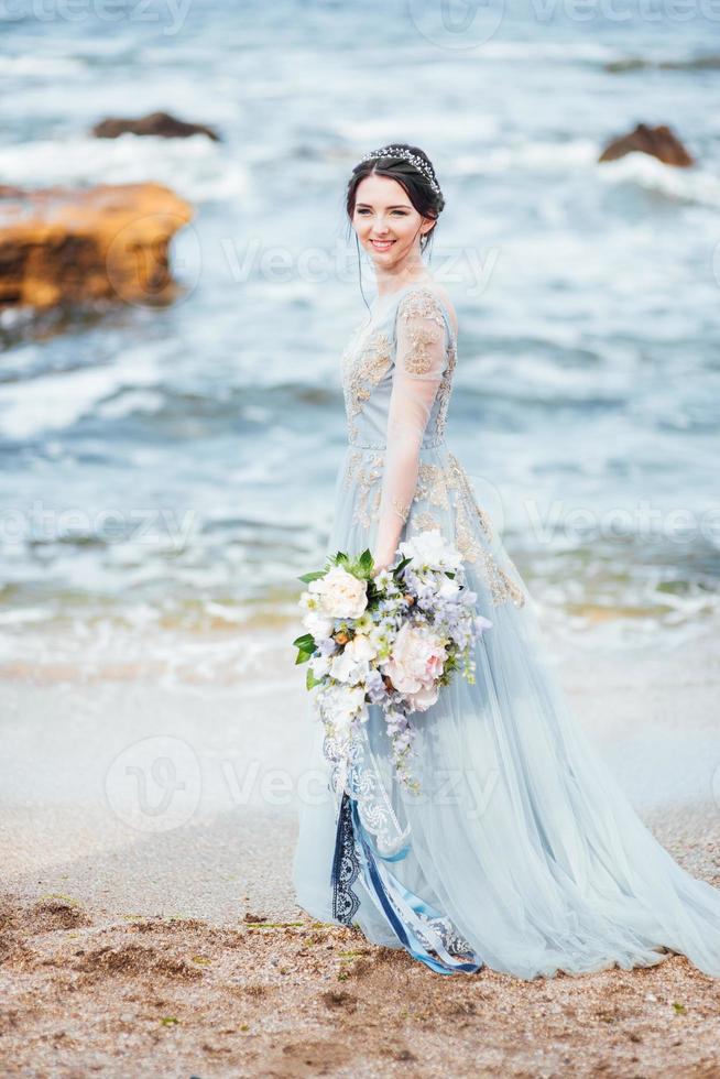 Braut mit einem Blumenstrauß am Strand foto