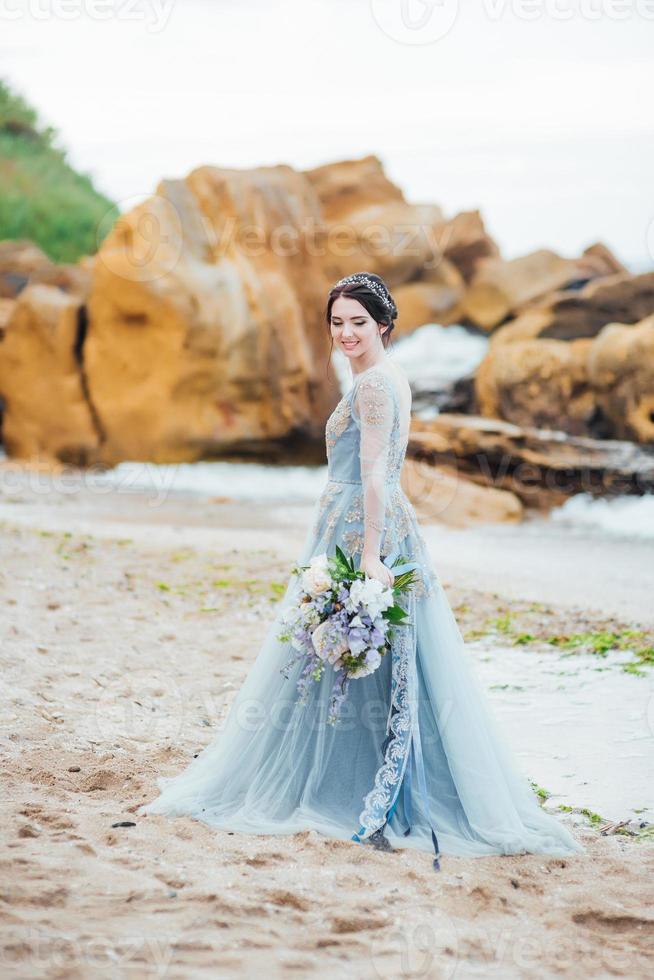 Braut mit einem Blumenstrauß am Strand foto