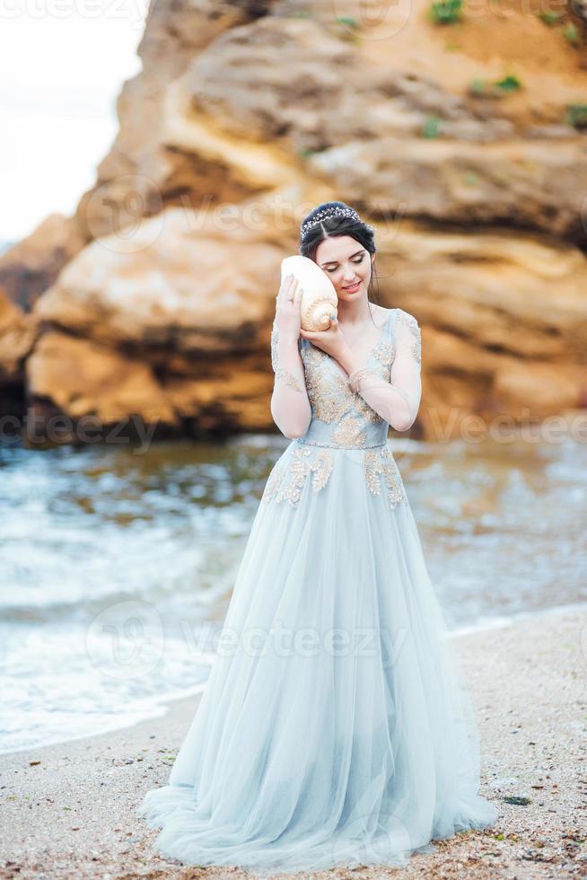 Braut mit einer großen Muschel am Strand foto