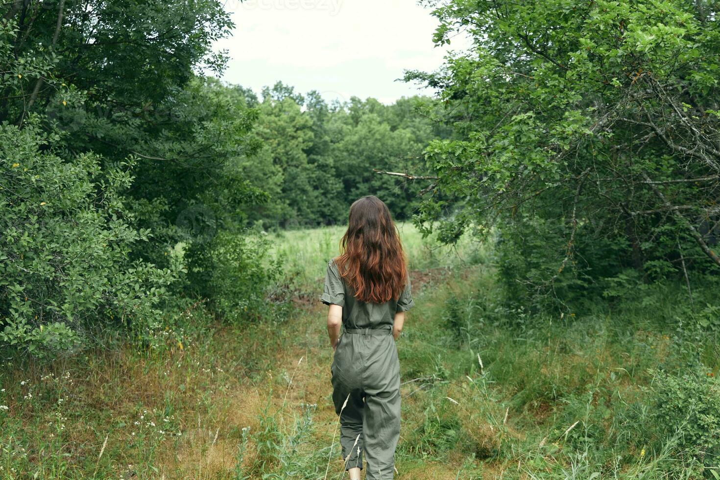 glücklich Brünette Frau im Overall auf das Wiese zurück Aussicht foto