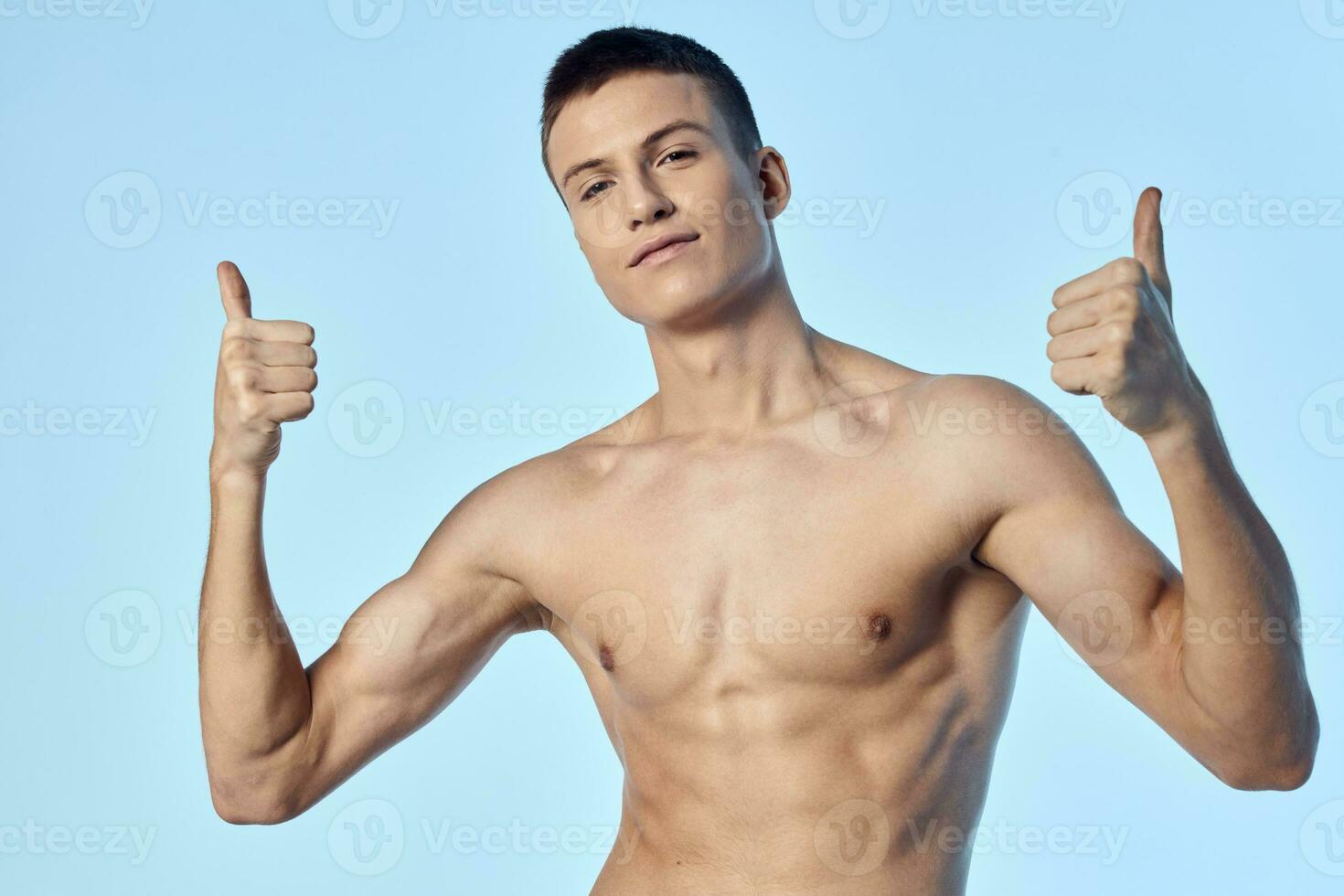 sportlich Mann mit nackt Torso zeigen Daumen auf Blau Hintergrund foto