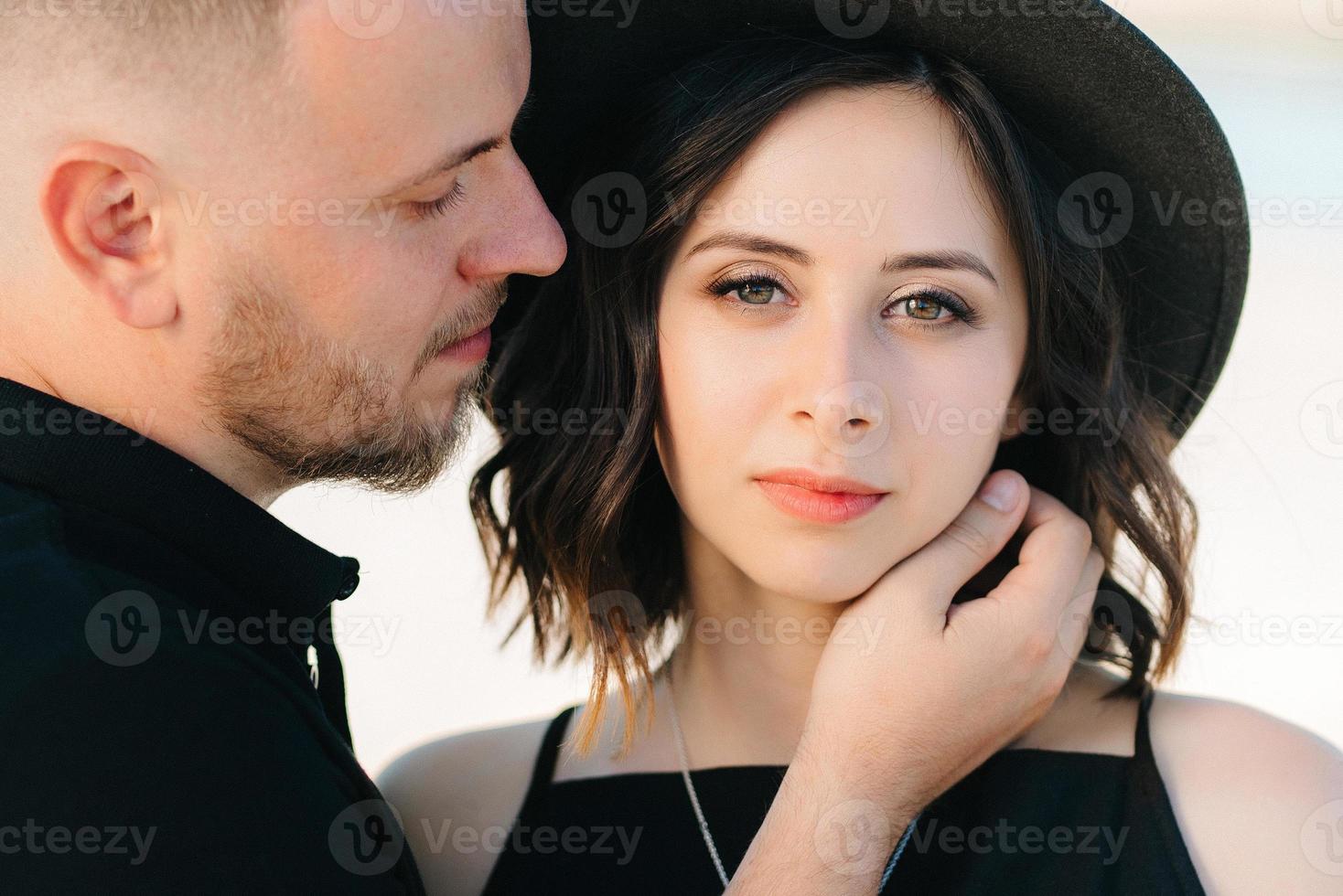 junges Paar ein Mann und ein Mädchen mit freudigen Gefühlen in schwarzen Kleidern gehen durch die weiße Wüste foto