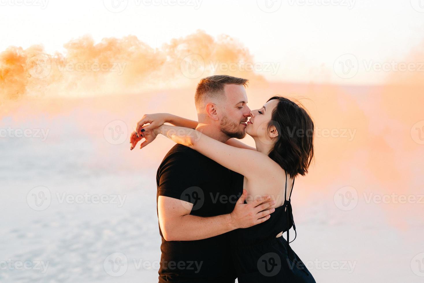 Mann und ein Mädchen in schwarzer Kleidung umarmen sich und rennen auf dem weißen Sand foto