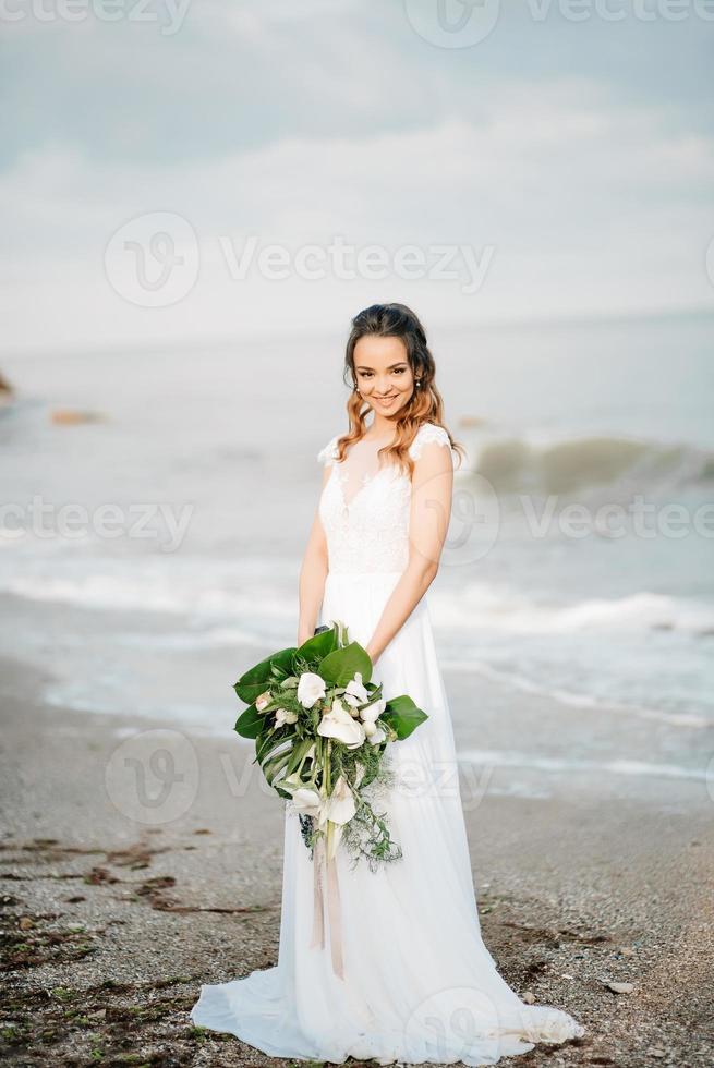 Braut mit einem Hochzeitsstrauß am Ufermeer foto