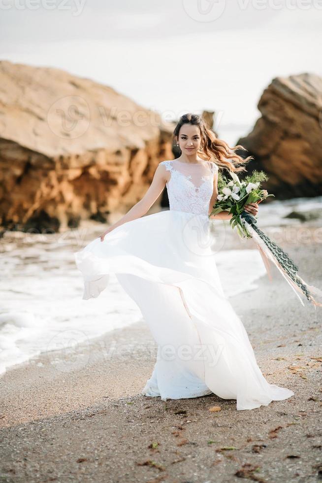 Braut mit einem Hochzeitsstrauß am Ufermeer foto