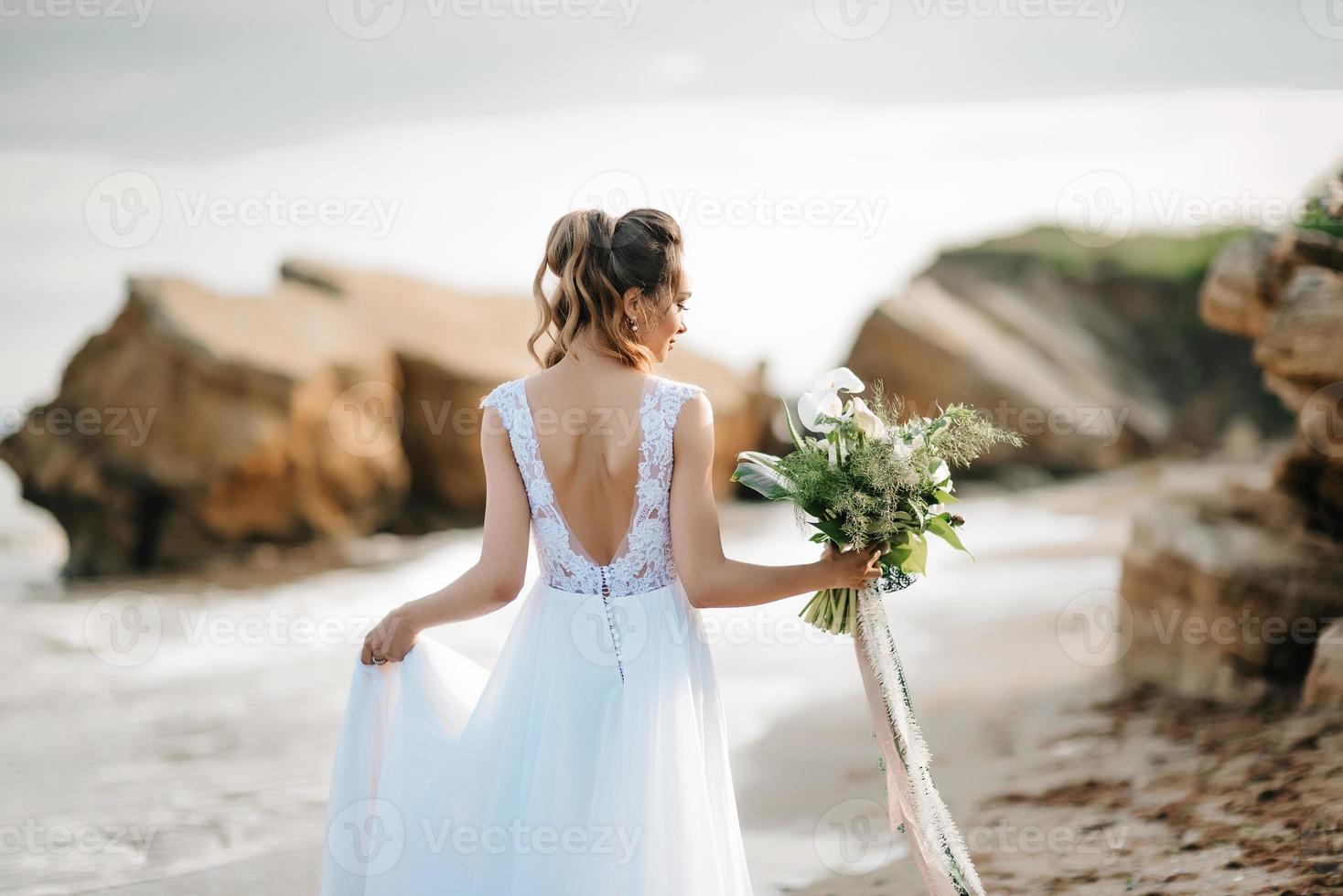 Braut mit einem Hochzeitsstrauß am Ufermeer foto