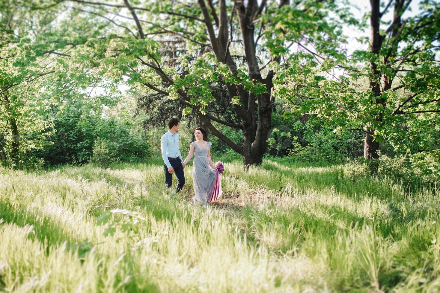 Ein Mann und ein Mädchen gehen im Frühlingsgarten der Flieder spazieren foto