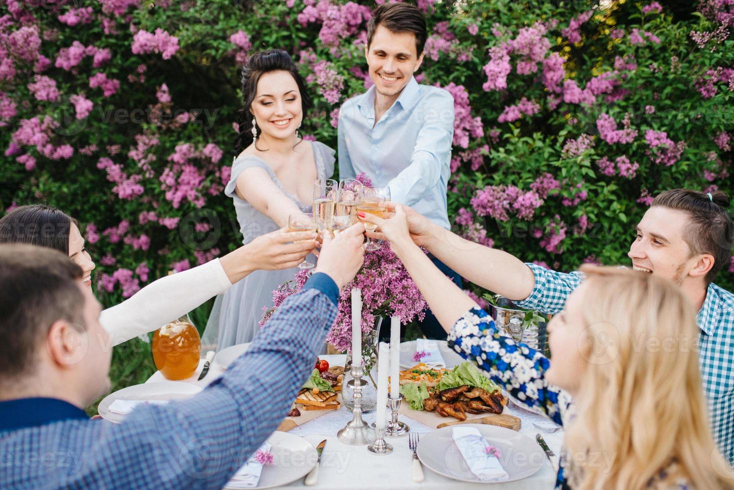 Braut und Bräutigam an einem Hochzeitstisch mit Freunden foto