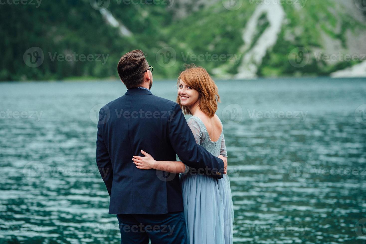 junges Paar auf einem Spaziergang in der Nähe des Sees, umgeben von den Bergen foto