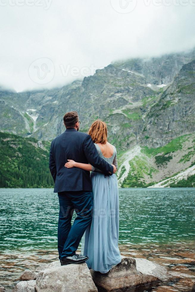 junges Paar auf einem Spaziergang in der Nähe des Sees, umgeben von den Bergen foto