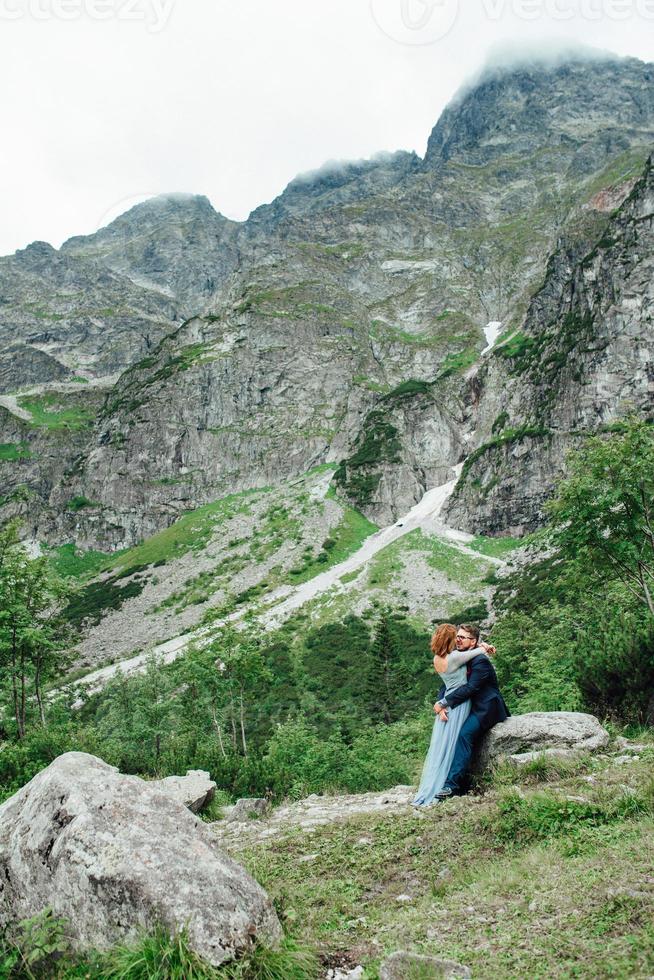 junges Paar auf einem Spaziergang in der Nähe des Sees, umgeben von den Bergen foto